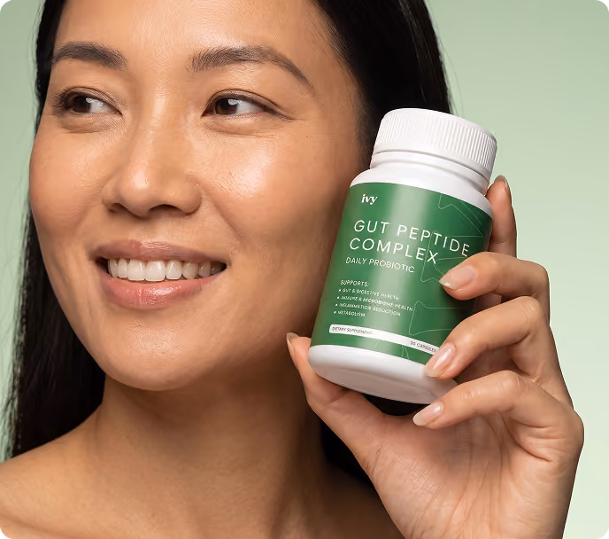 Smiling woman with curly hair holding a small vial labeled 'ivy GLP-1 Injection Rx only' against a teal background.