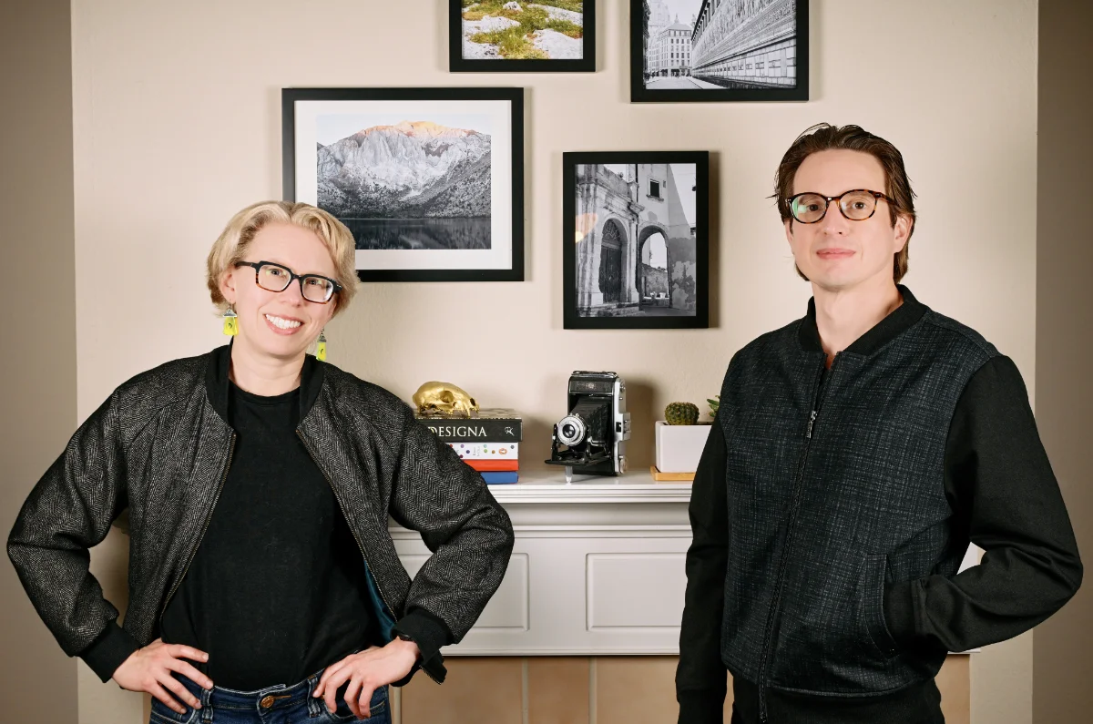 Two people standing in front of a fireplace posing for the camera.