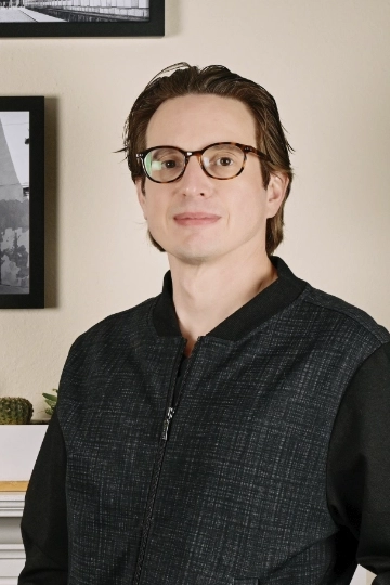 A man with glasses in a bomber jacket