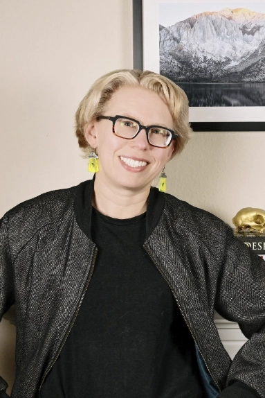 A woman with short blonde hair in a bomber jacket