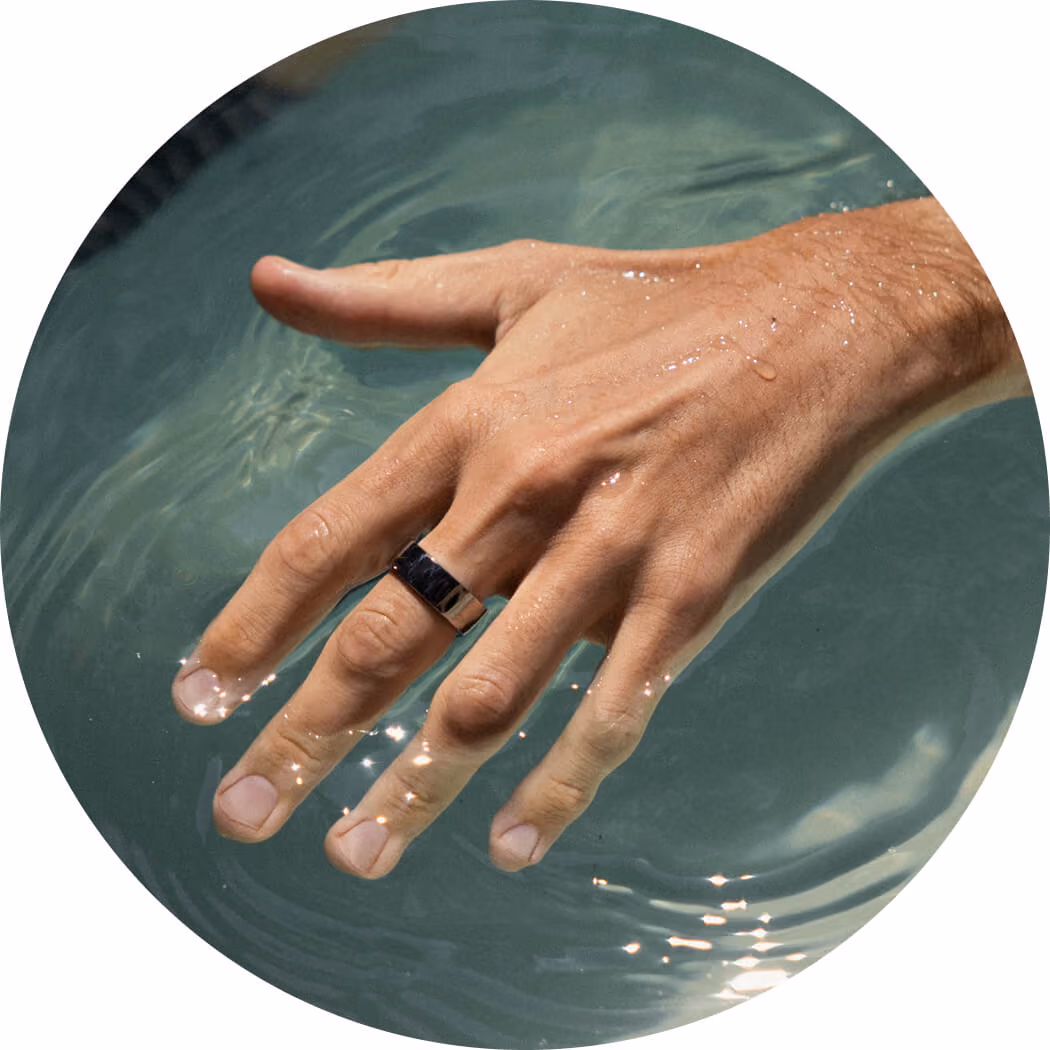 Close-up of a hand with a silver ring submerged in clear water with light reflections.