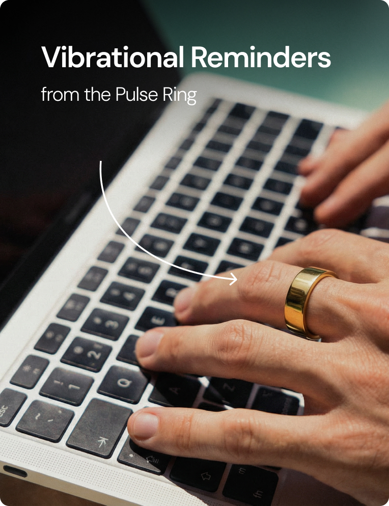 Hand wearing a gold Pulse Ring typing on a laptop keyboard with text Vibrational Reminders.