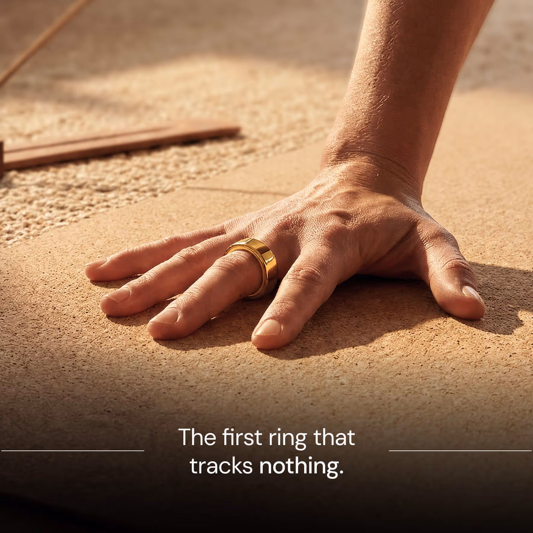 Hand with a wide gold ring on the ring finger resting on a textured surface with text below.