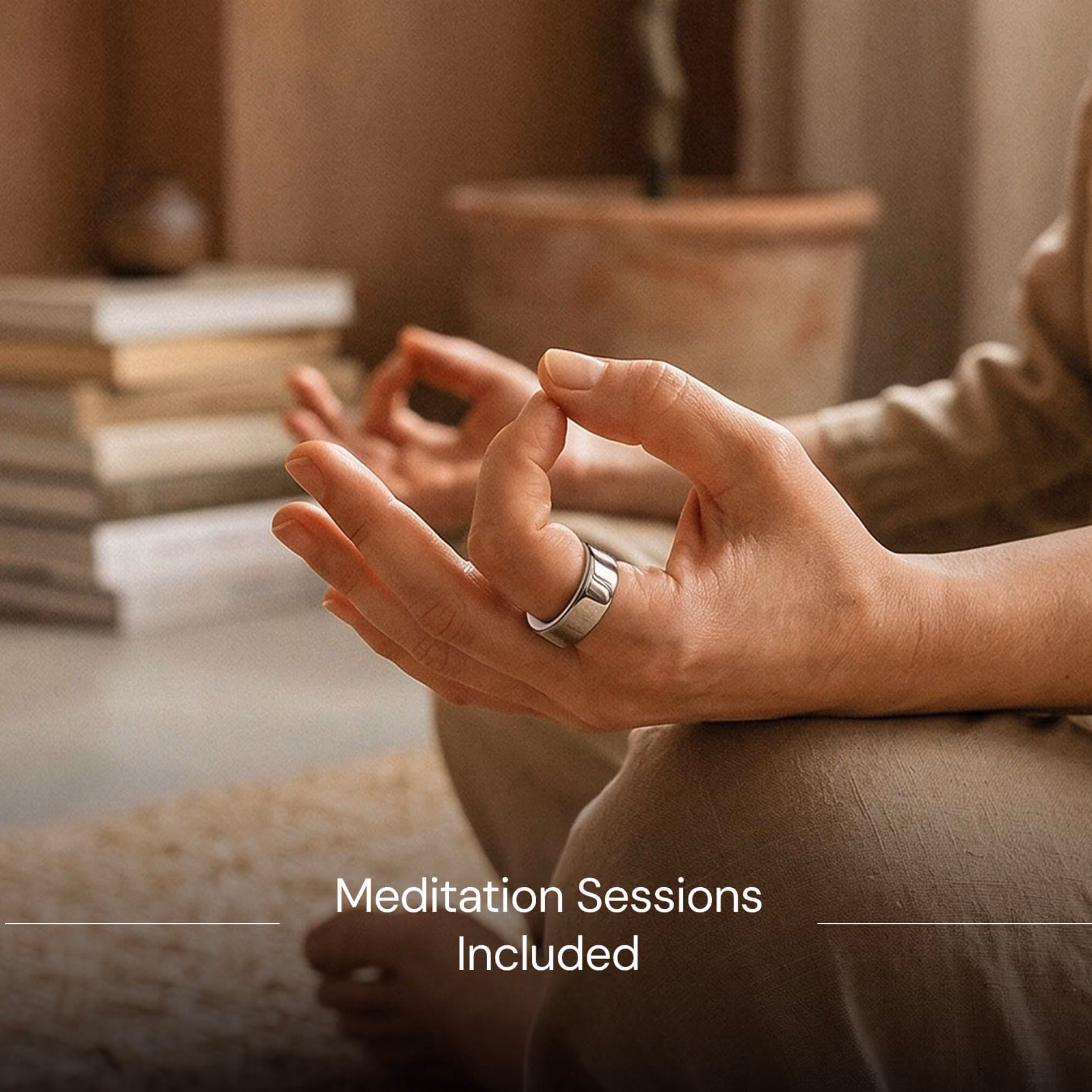 Close-up of hands in meditation mudra pose wearing a silver ring, with blurred books and plant in background.