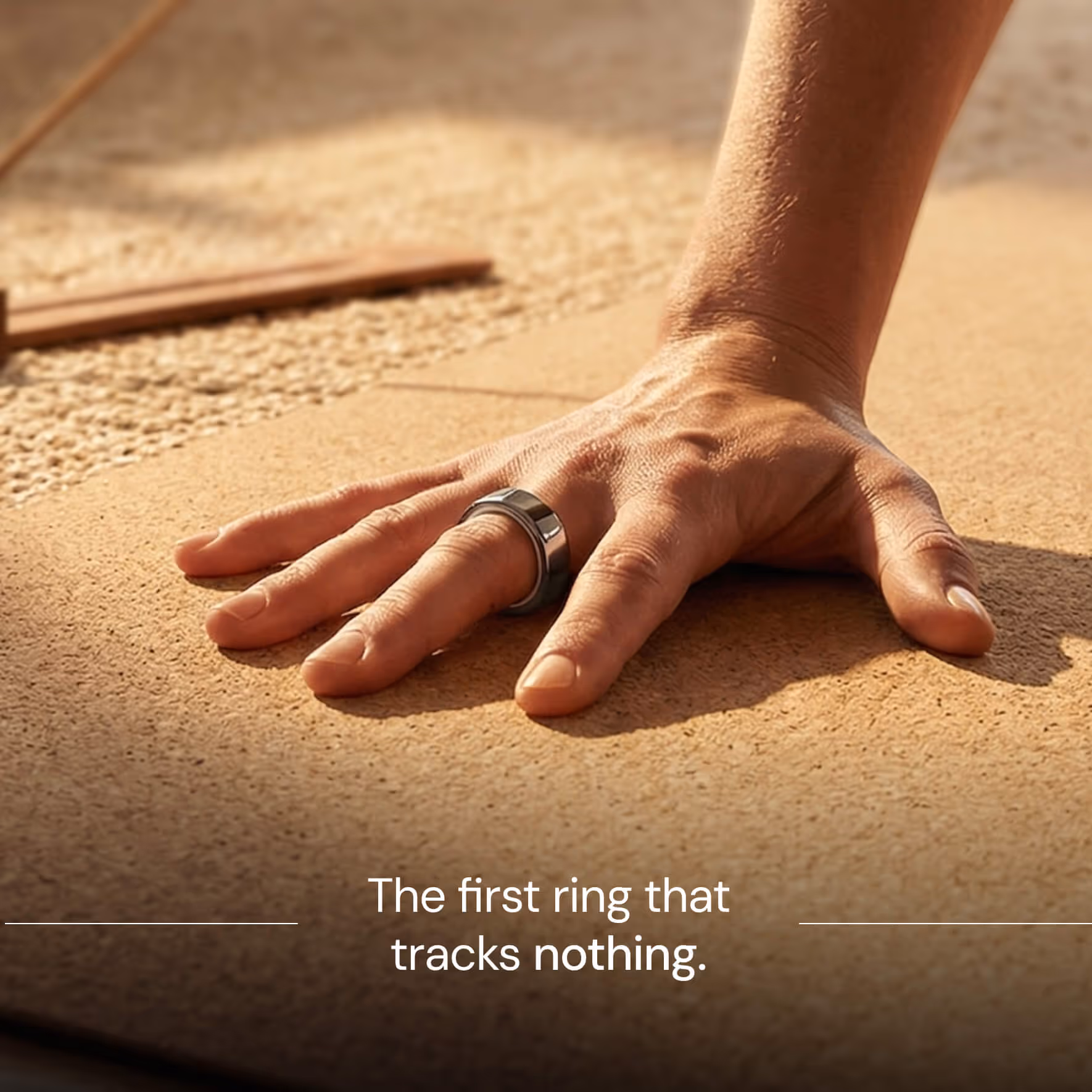 Hand resting on textured surface wearing a shiny gray ring on the middle finger.