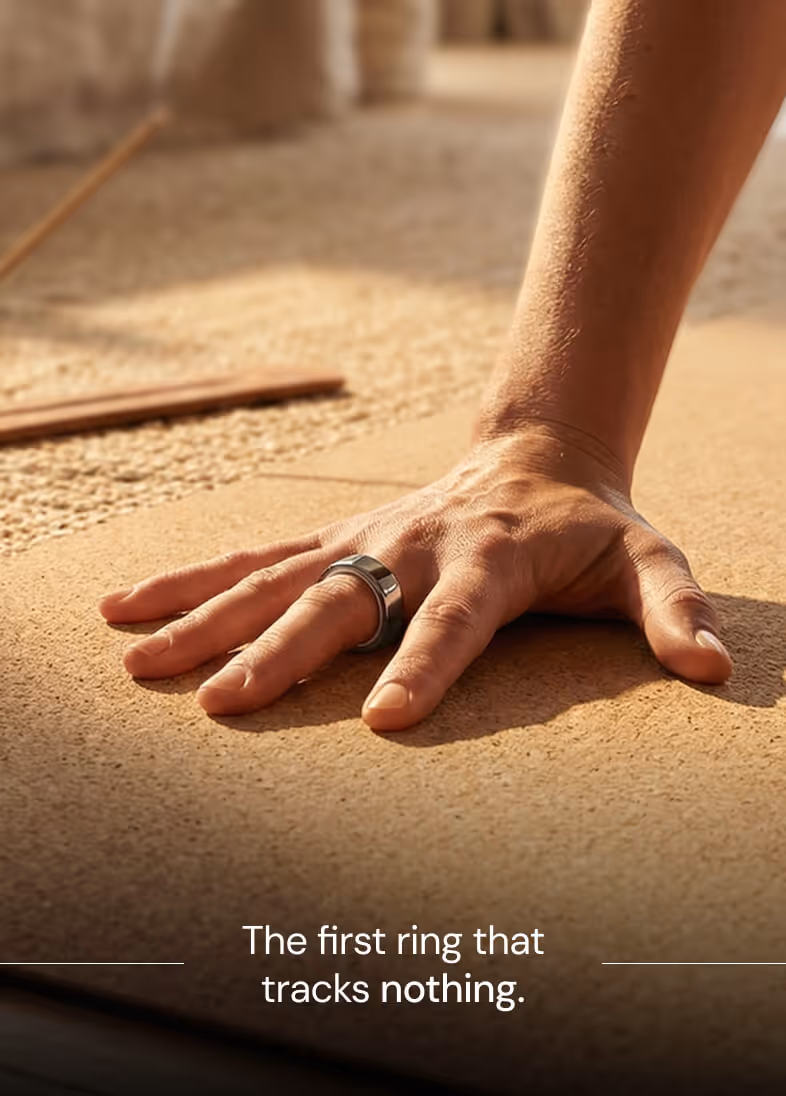 Hand with a sleek silver ring on the finger resting on a textured surface in warm lighting.