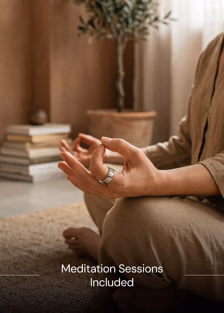 Person sitting cross-legged meditating indoors with a silver ring on their finger.