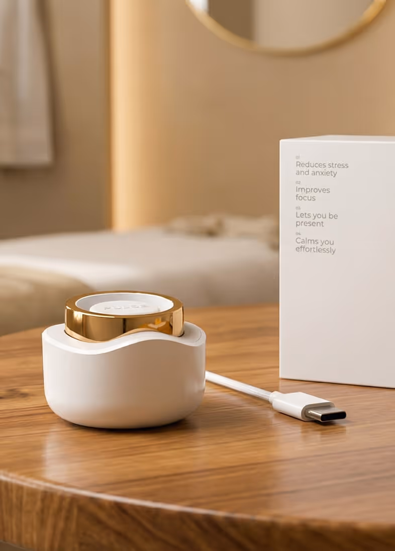 Gold and white wearable device in a white charger on a wooden table near a box with benefits text.