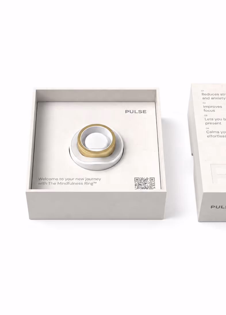 Gold mindfulness ring displayed on a white stand inside a minimalistic box labeled Pulse.