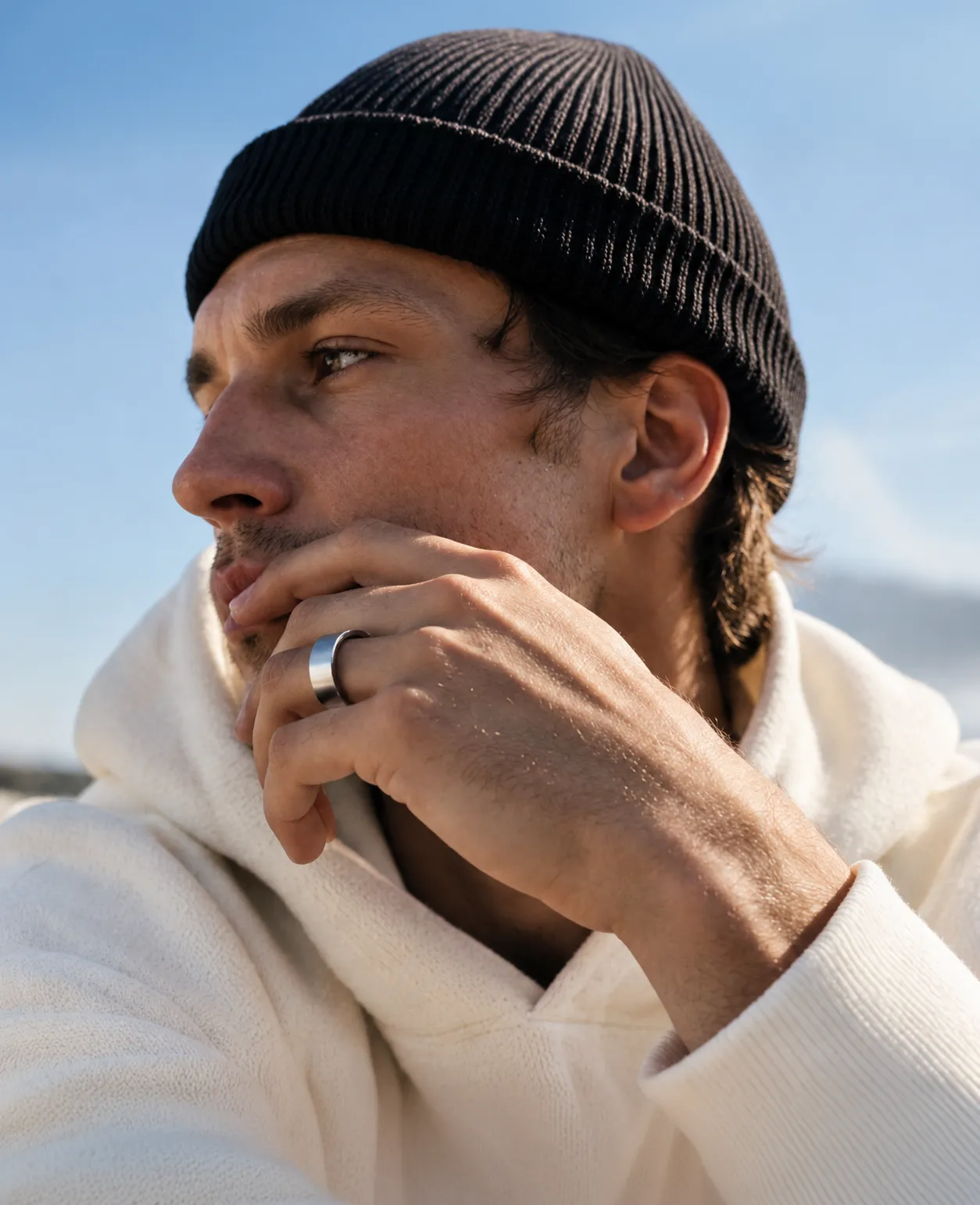 A man in a beanie resting his chin on his hand, wearing the Pulse Ring.