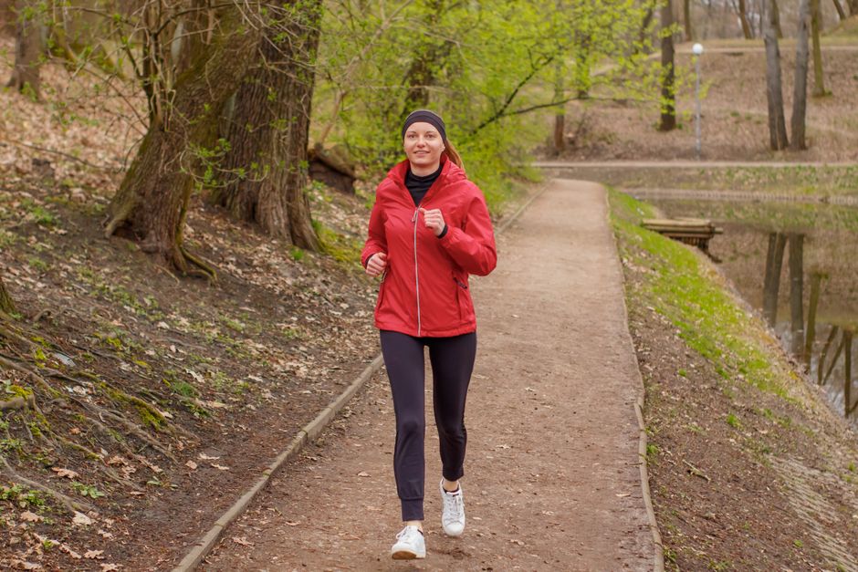 Femme pratiquant le running régulièrement dans un parc urbain