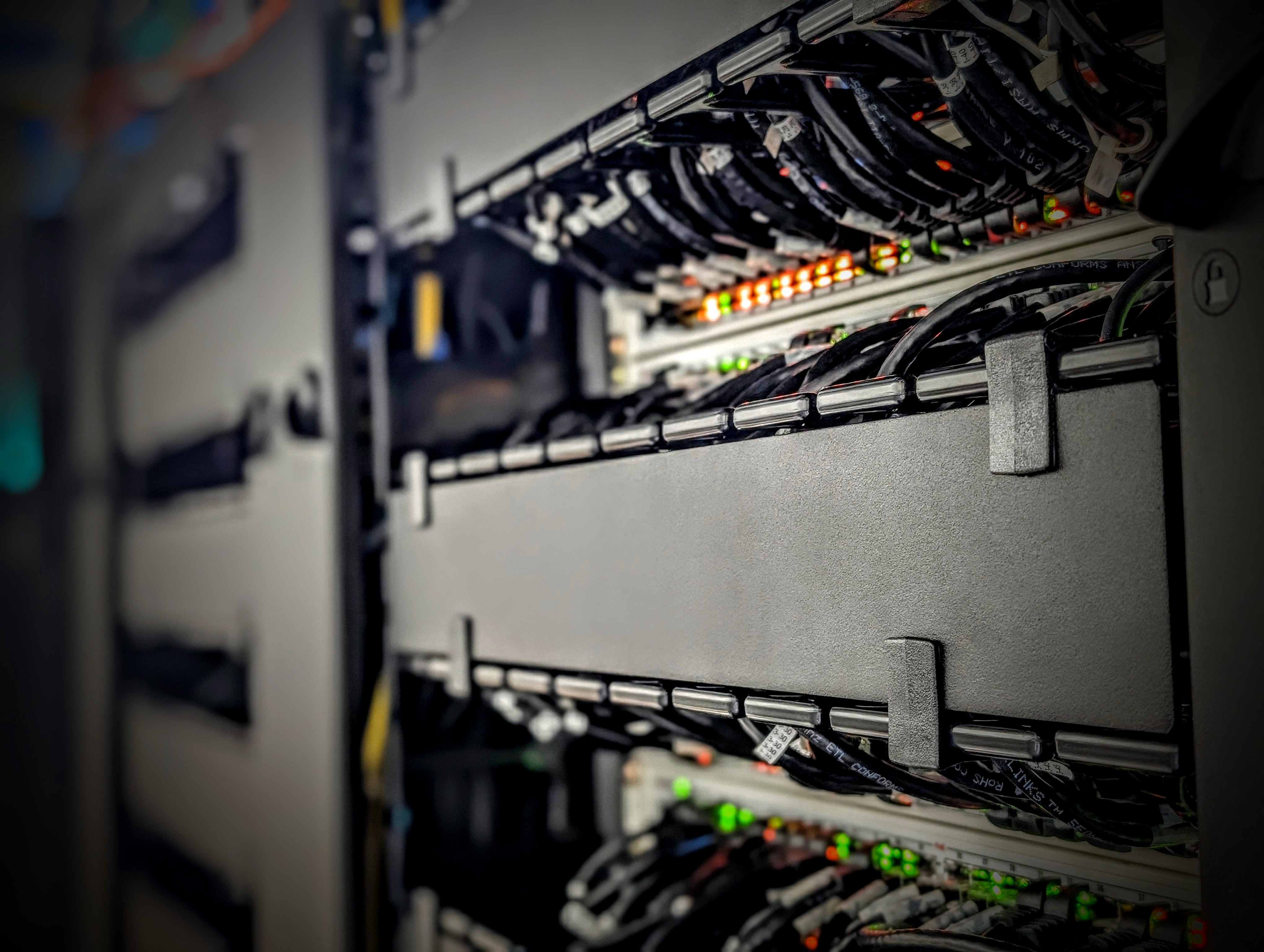 Close-up of a server rack with multiple network cables and illuminated status indicator lights in a data center.