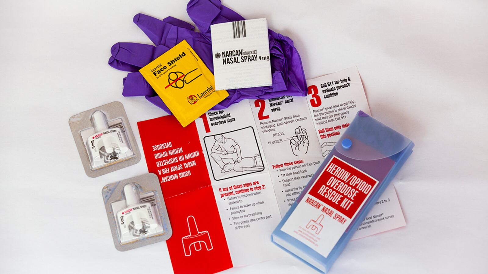 Heroin/opioid overdose rescue kit including Narcan nasal spray, gloves, face shield, and instruction leaflet.