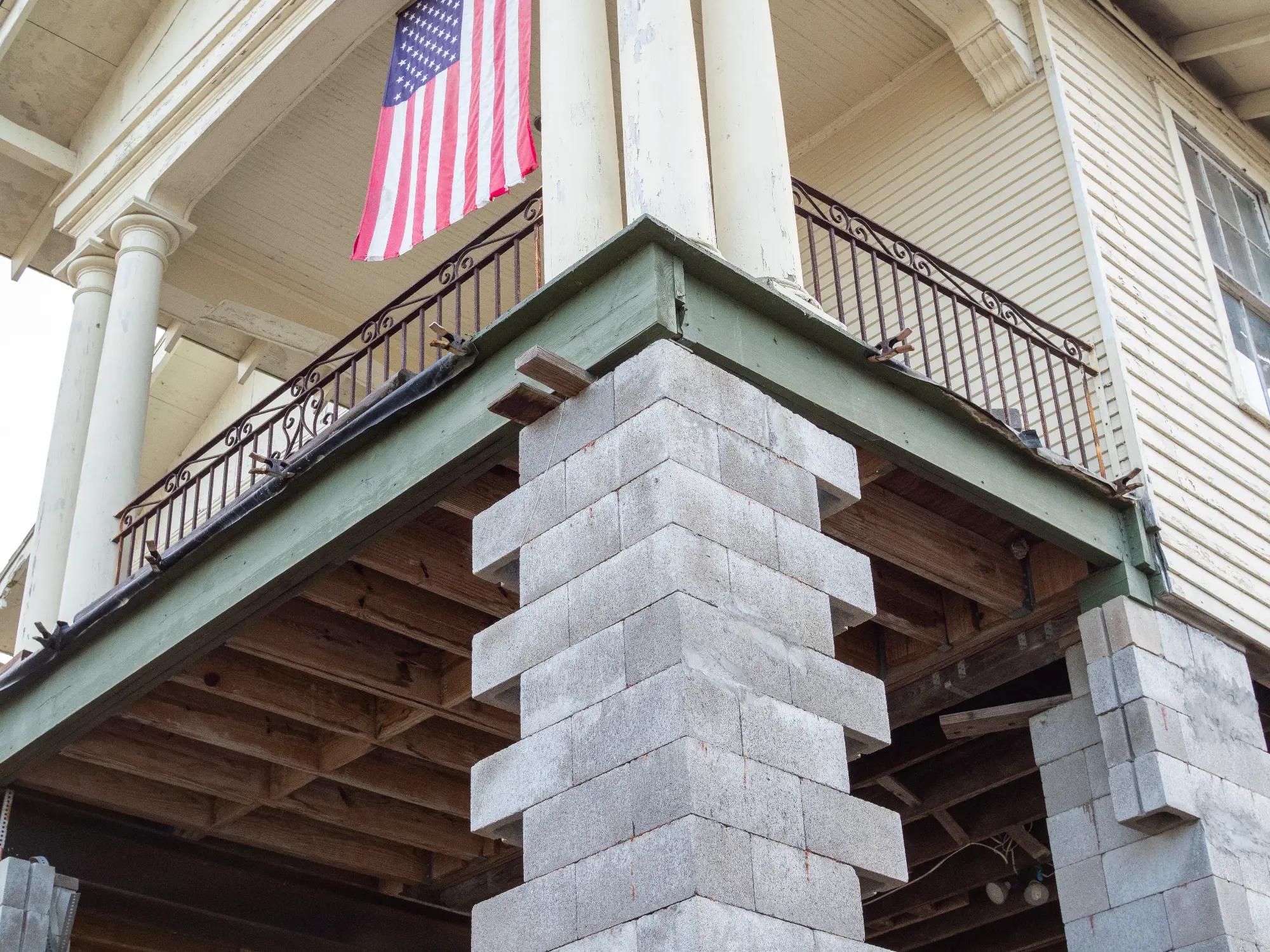 Exterior view of a wooden building supported by cinder block pillars with an American flag hanging on the porch.