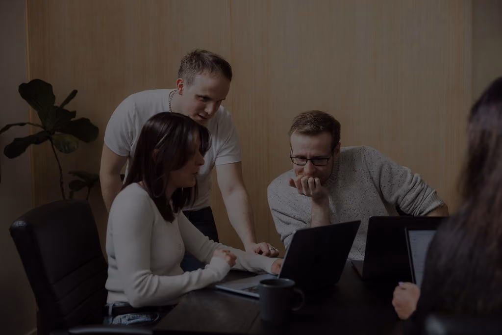 FireNet Designs team collaborating around a laptop in the studio.