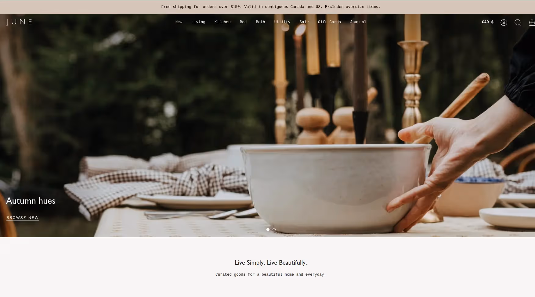 A hand holds a wooden spoon in a large bowl on an outdoor table set with plates, napkins, and candles.