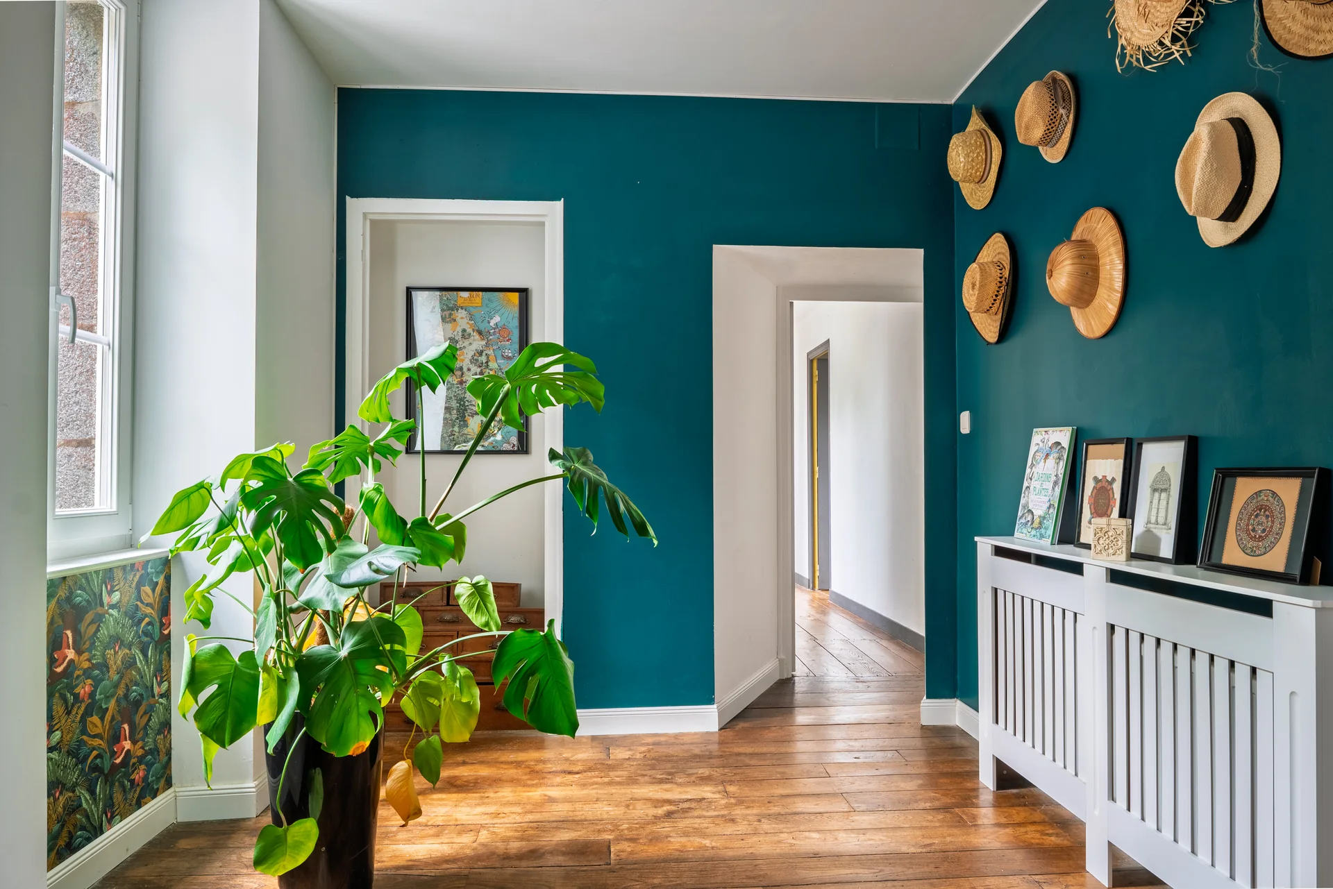 Couloir d'entrée aux murs bleu canard décoré de chapeaux, shooting immobilier de l'agence Apollo pour Kretz