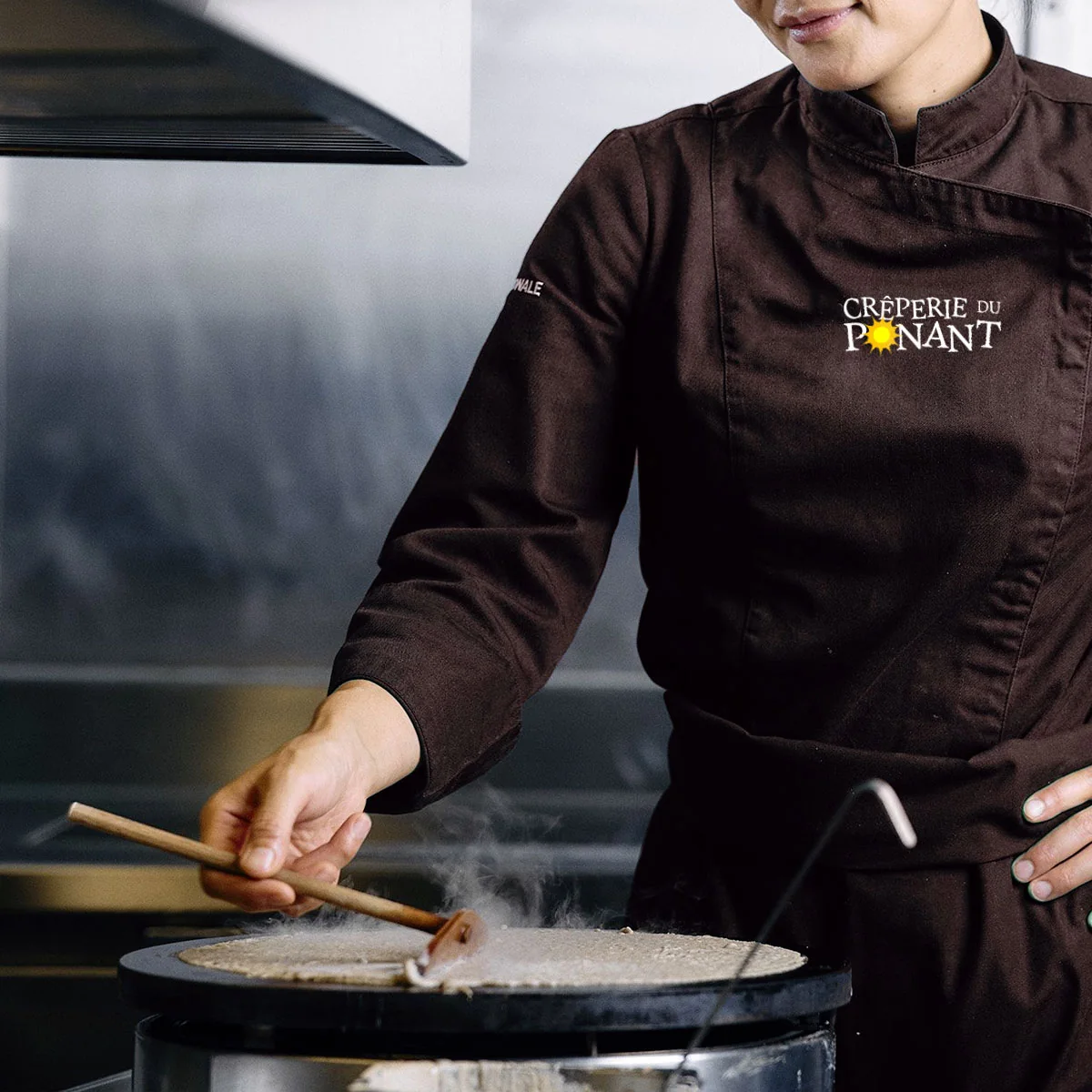 Tablier brodé Crêperie du Ponant porté en cuisine, concept graphique de l'agence Apollo