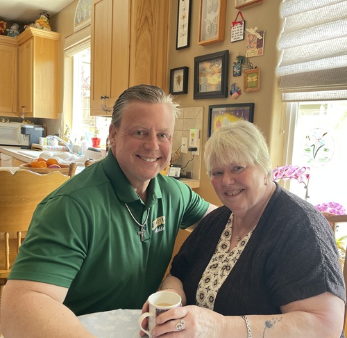 An adult son and mom in kitchen smilling