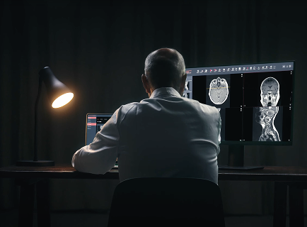 A man working at a desk lit by a single lamp in a dark room