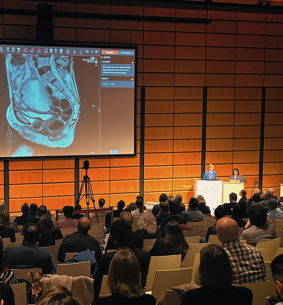 A full conference audience watching a large presentation screen