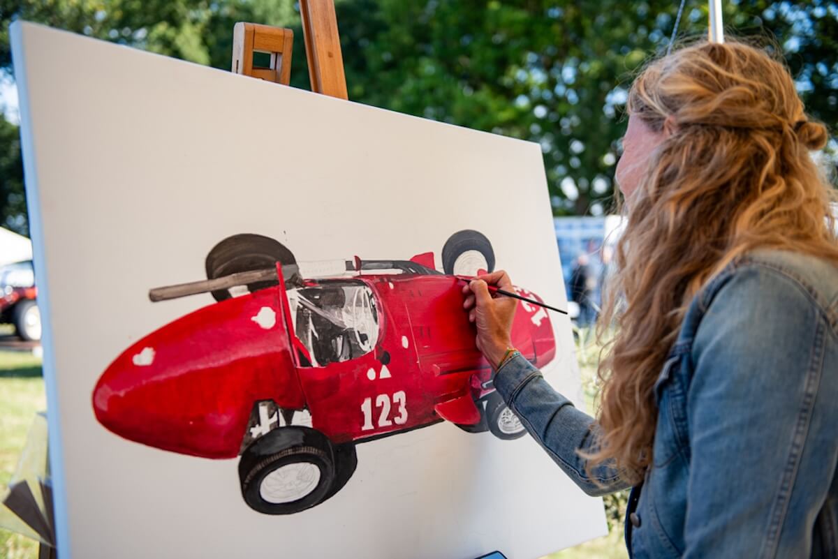 Kunstenaar schildert een rode racewagen tijdens Wheels Mariënwaerdt