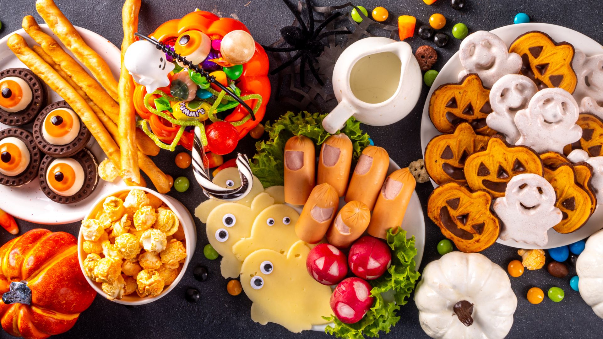 Spooky Halloween office catering buffet with themed snacks, pumpkin cookies, ghost-shaped treats, and finger food