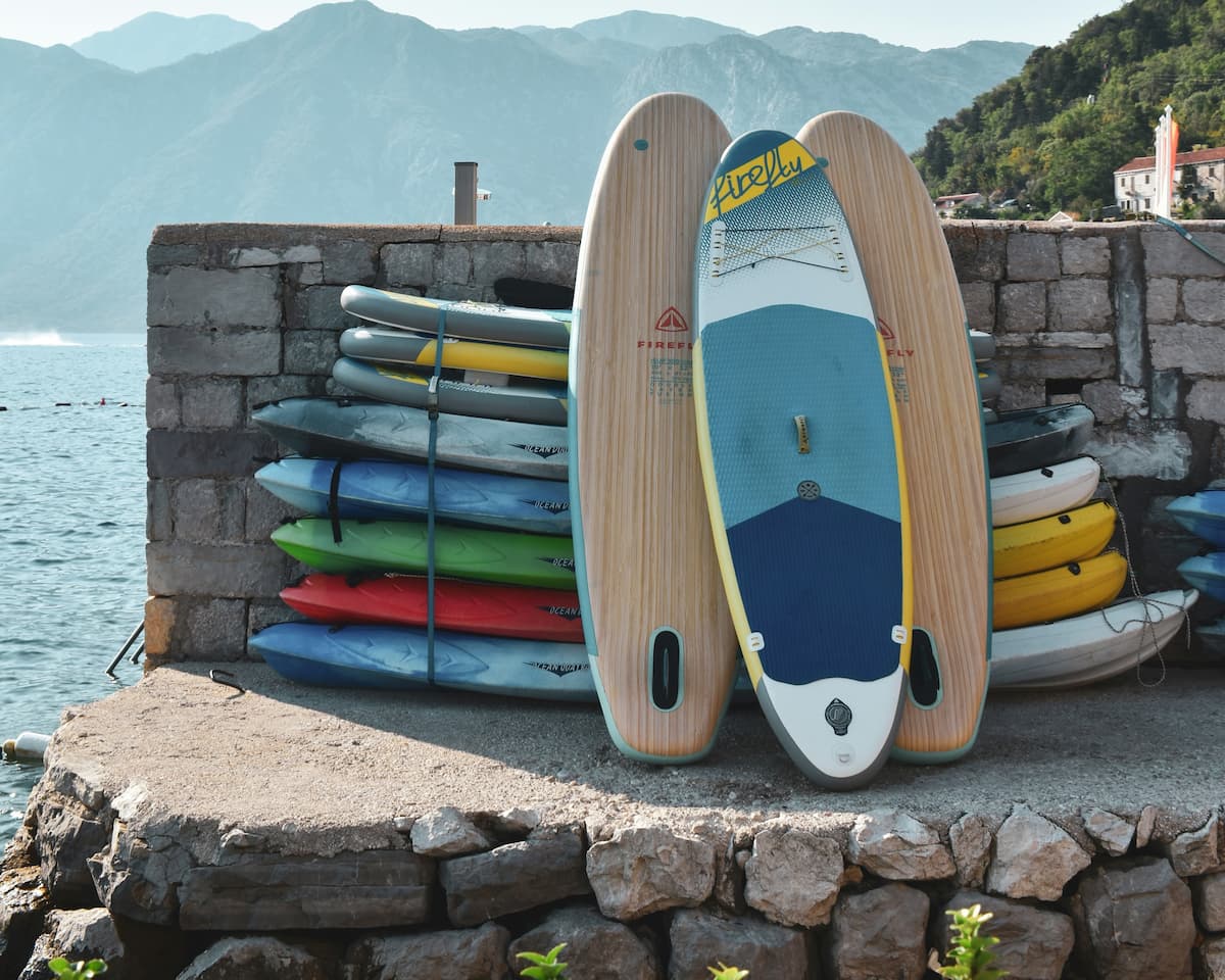 Paddle boards and kayaks stacked beside the water
