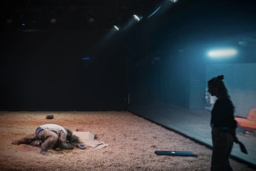 Aktor leżący na ziemi i idąca obok aktorka. Fot: Piotr Nykowski