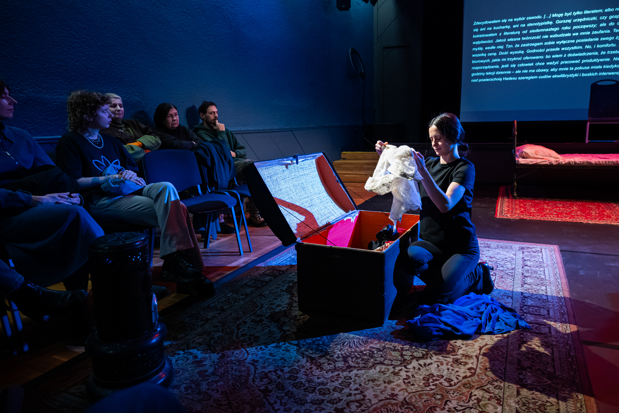 Aktorka klęcząca przy kufrze z ubraniami. Fot. Kornelia Głowacka-Wolf