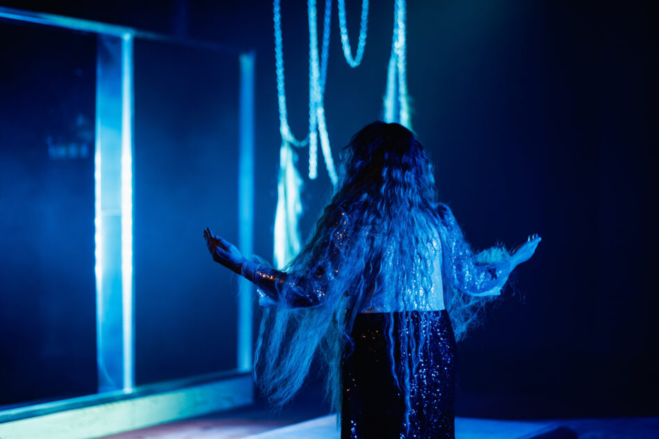 Aktorka w niebieskim świetle z rozłożonymi rękoma. Fot. Bartek Warzecha