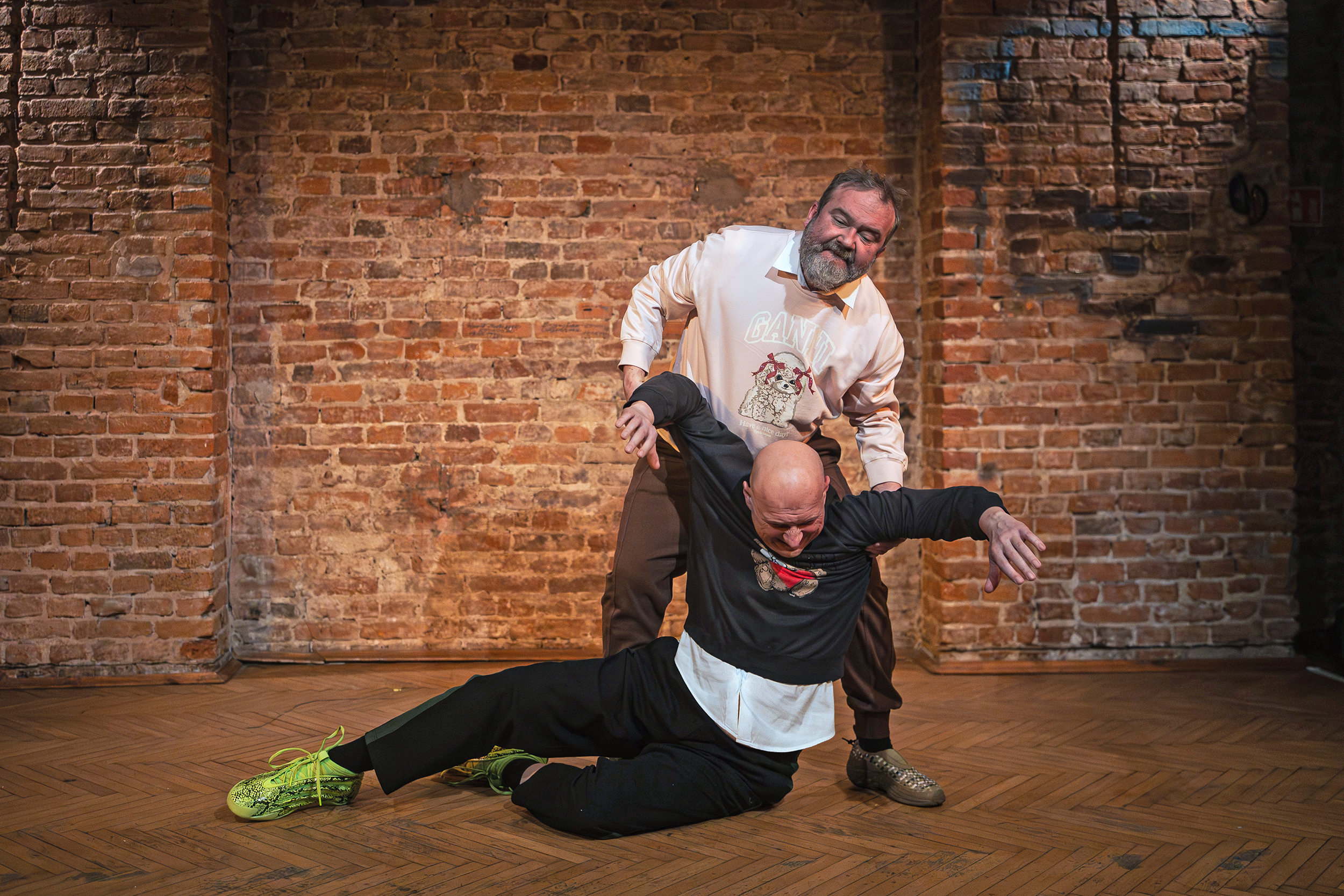 Aktor próbuje podnieść siedzącego na ziemi partnera. Fot. Tomasz Bąk