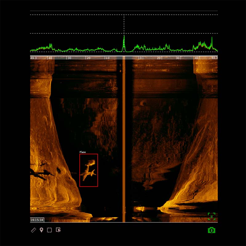 Sonar image showing underwater cliffs with a detected airplane highlighted in a red box on the left side.