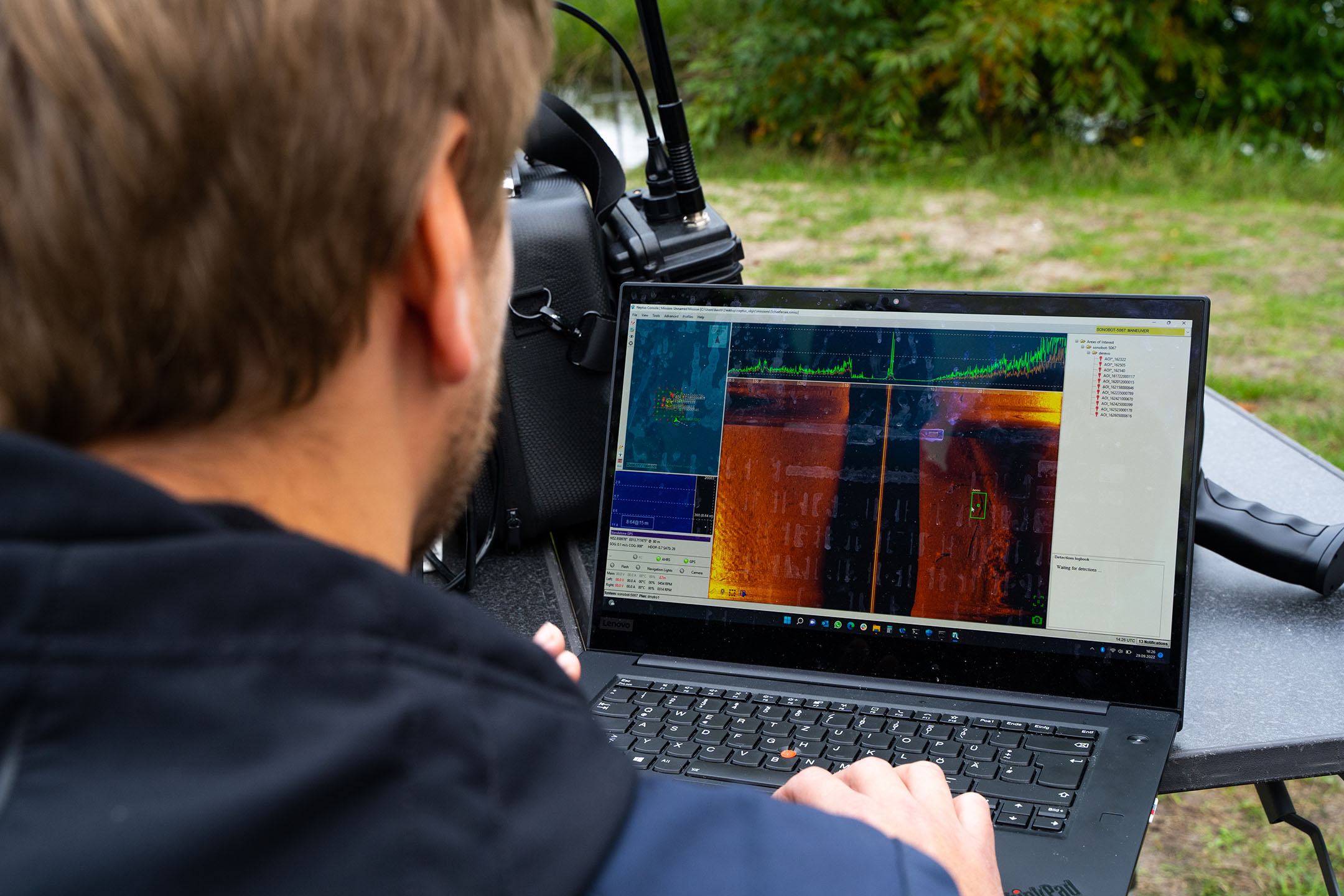 Man operating remote sensing software on a Lenovo laptop outdoors.