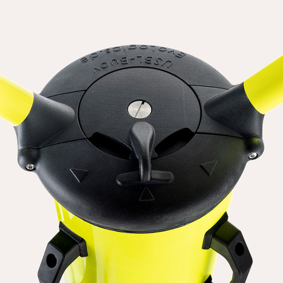 Close-up top view of a black and yellow USBL buoy component with a central screw and a turning handle.