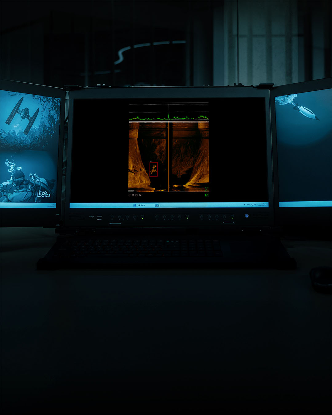 Three computer monitors with underwater-themed images, center screen displaying sonar scan with detected object.