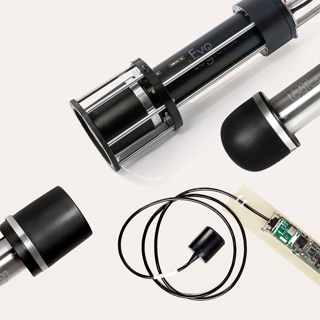 Close-up of black and metallic cylindrical electronic components and a circuit board with connected cables on a white background.