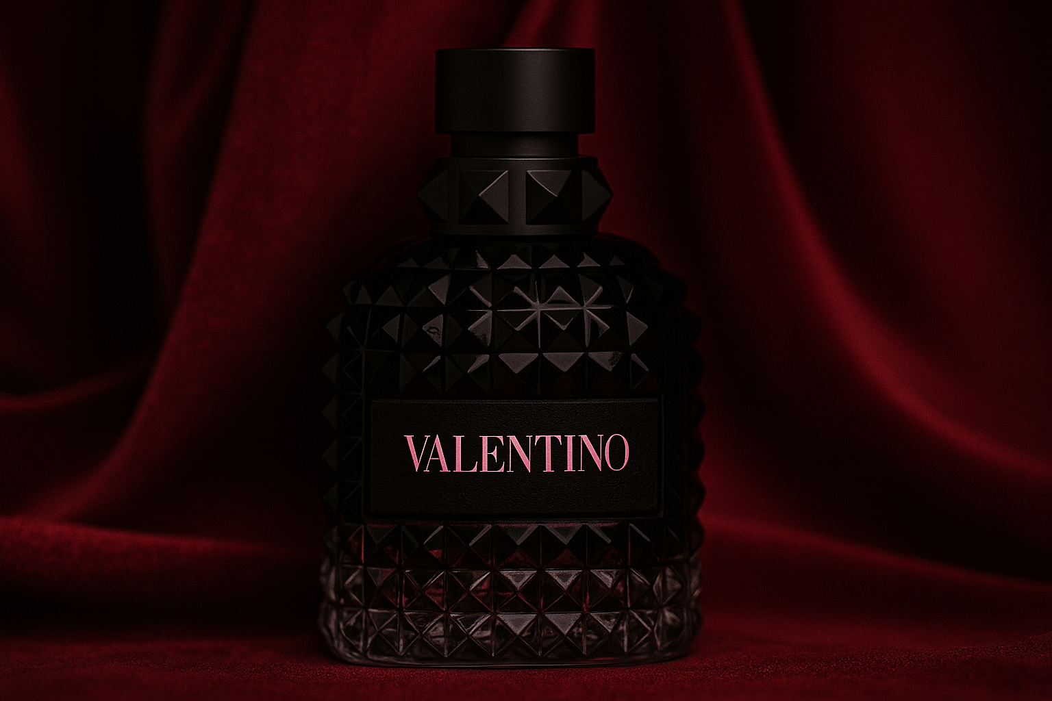 Valentino fragrance bottle with black studded glass and pink logo, placed against a deep red velvet fabric background under soft lighting.