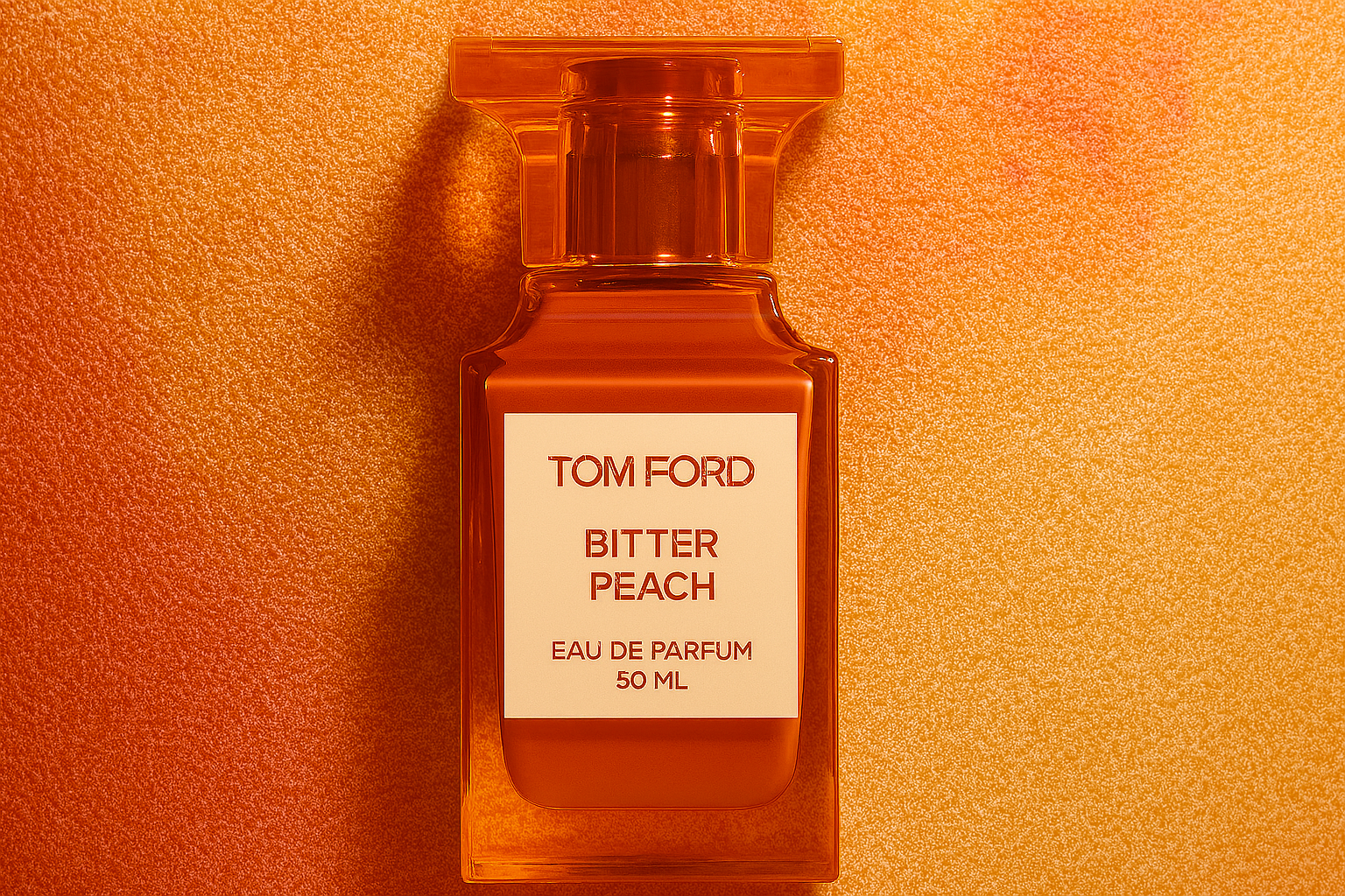 Tom Ford Bitter Peach perfume bottle with orange translucent cap, placed on a textured peach-toned background.