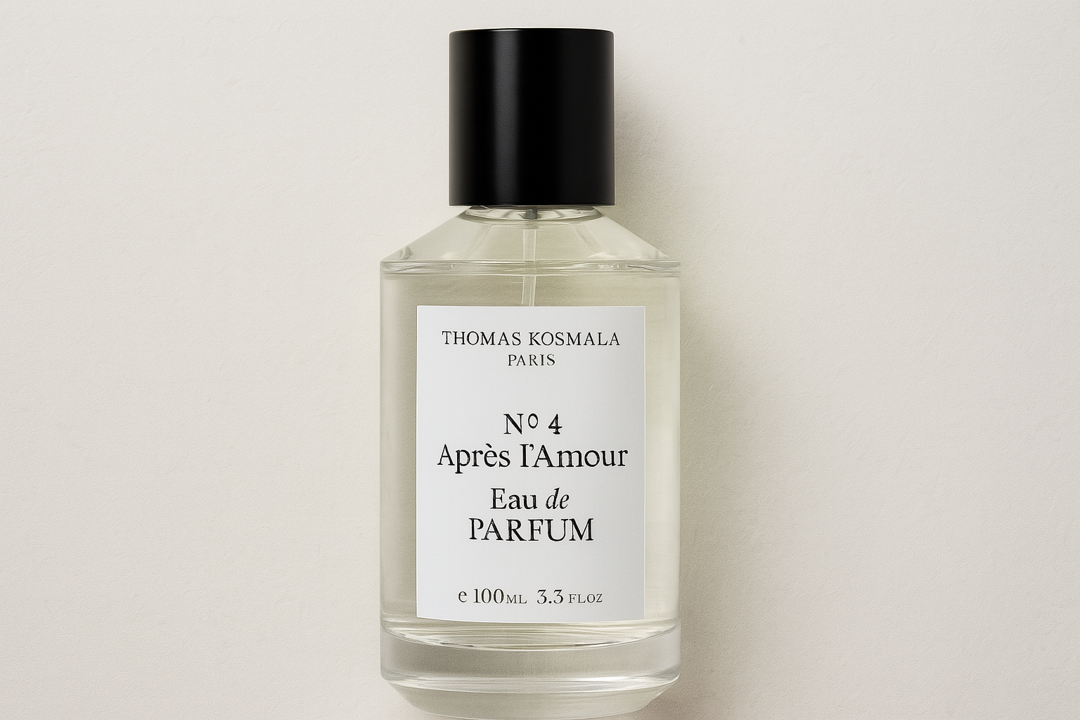 A realistic widescreen image of Thomas Kosmala No.4 Après l’Amour Eau de Parfum bottle with clear liquid, black cap, and white label, set against a light textured background.