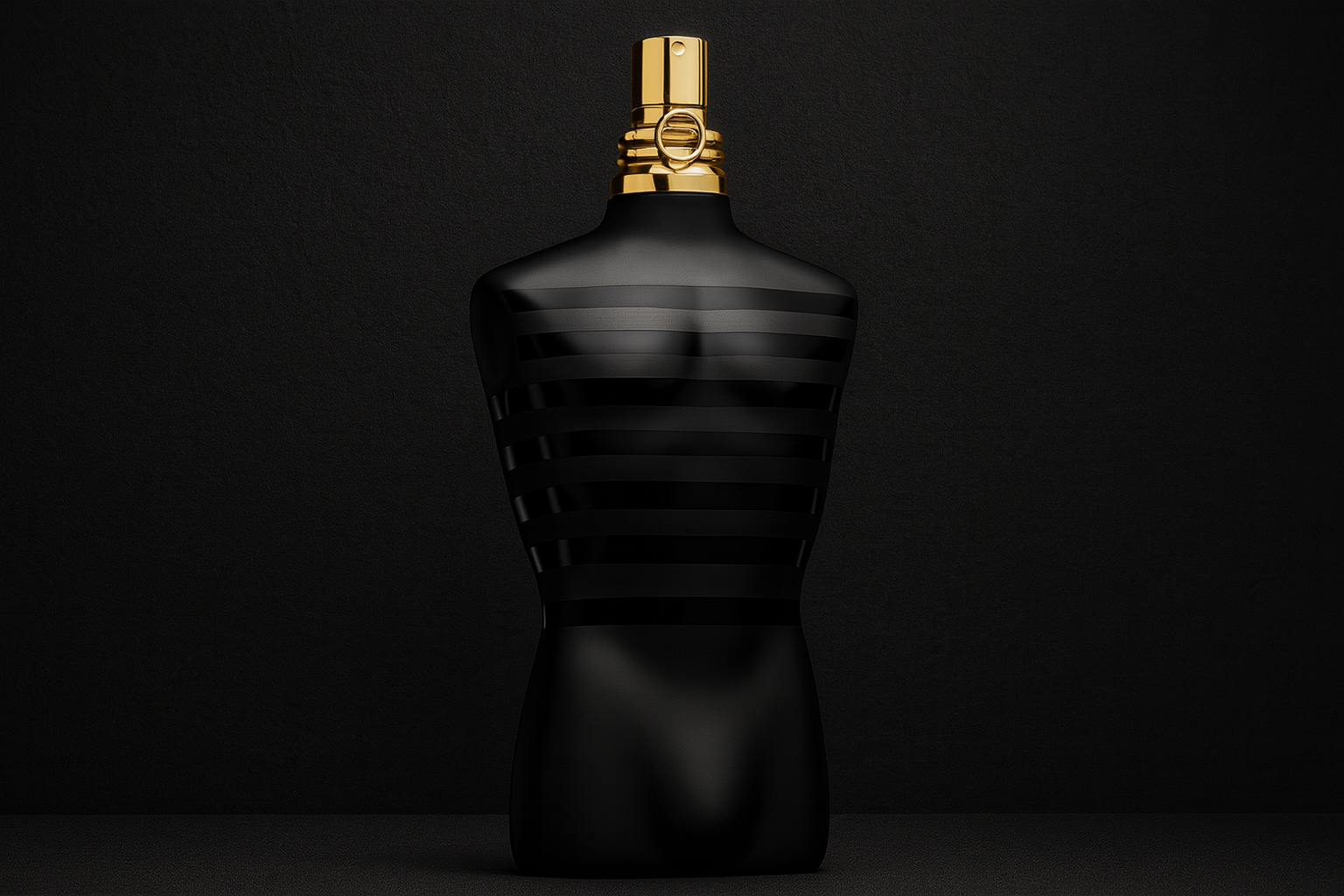 A realistic widescreen image of Jean Paul Gaultier Le Male Le Parfum bottle shaped like a black torso with matte and glossy stripes, topped with a gold atomiser, set against a dark black background.