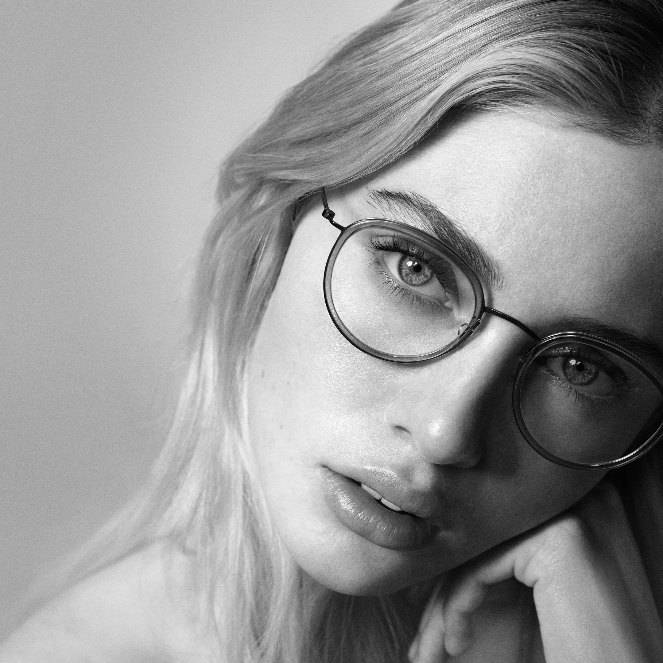 Black and white portrait of a thoughtful person wearing large round glasses