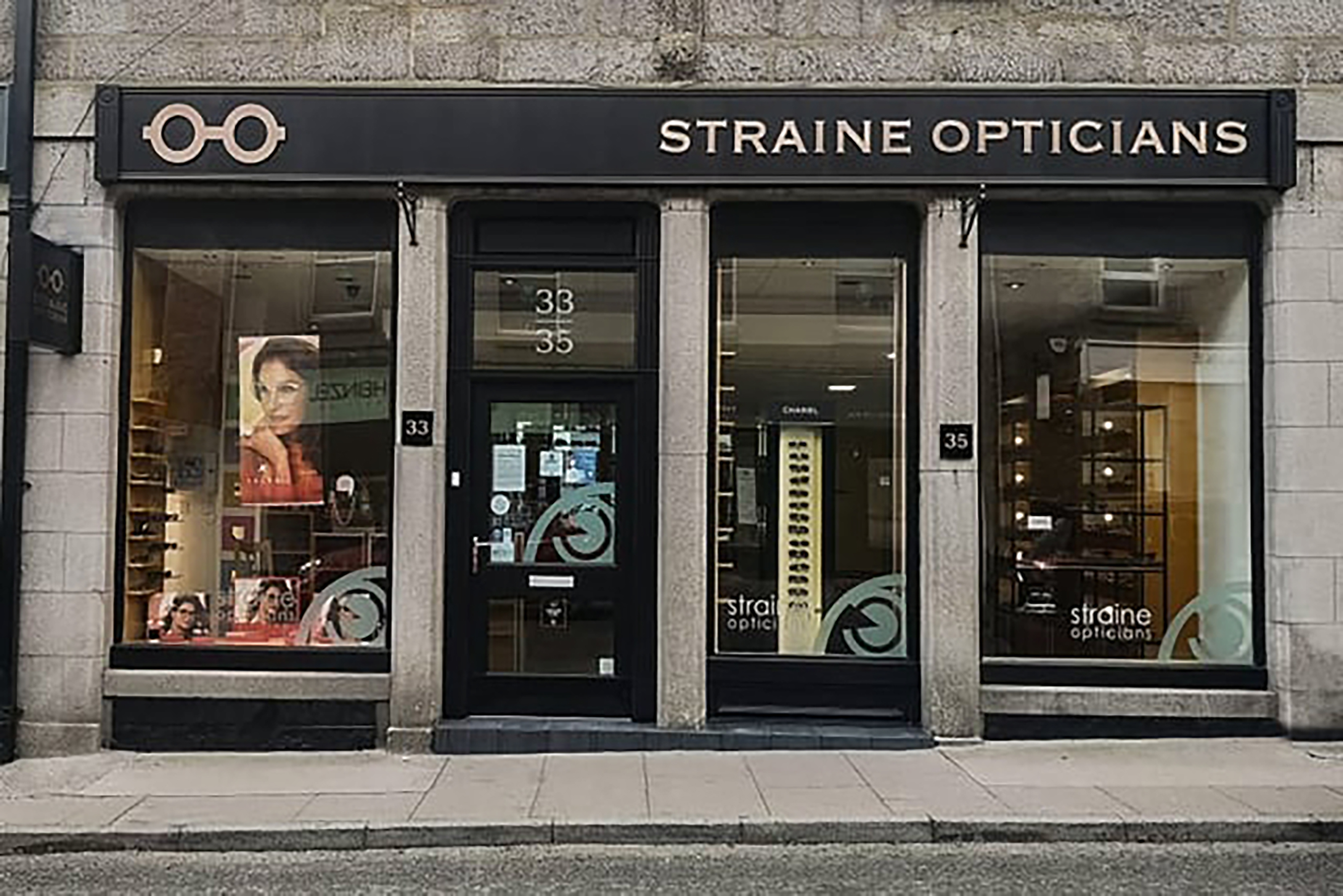Straine Opticians storefront with glasses display and advertising posters