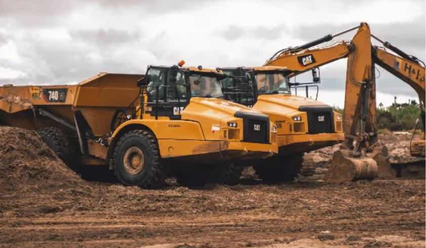 A large yellow construction vehicle sitting on top of a dirt field.