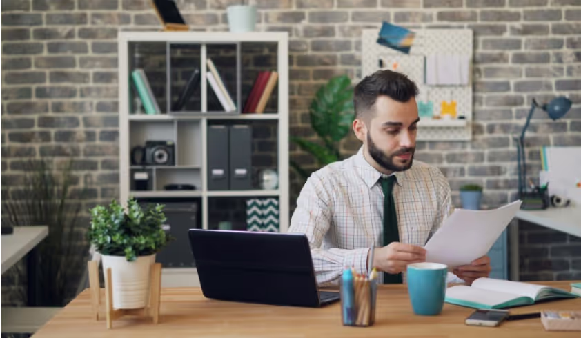 A man sitting at a desk in front of a laptop.