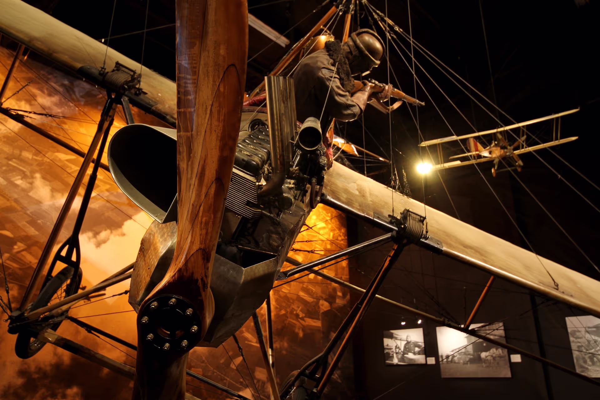 Vintage airplane with wooden frame on display in a dimly lit museum.