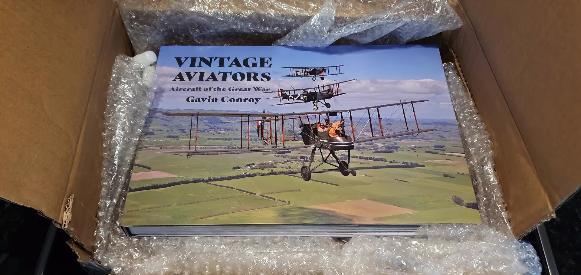 A book titled "VINTAGE AVIATORS Aircraft of the Great War Gavin Conroy" inside a bubble-wrapped shipping box.