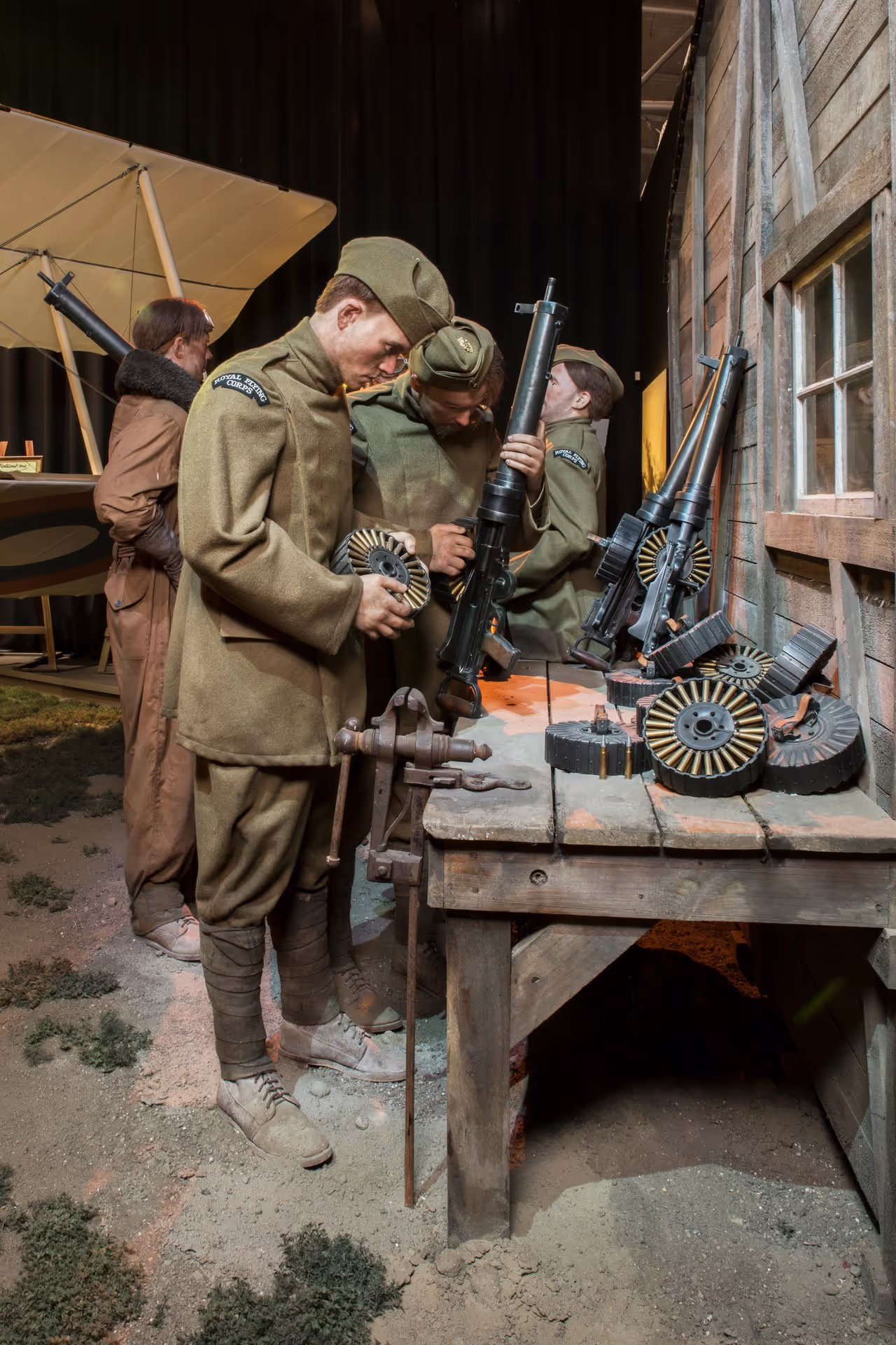 A reinaction of soldiers in WWI uniforms handling period weapons beside a vintage aircraft.