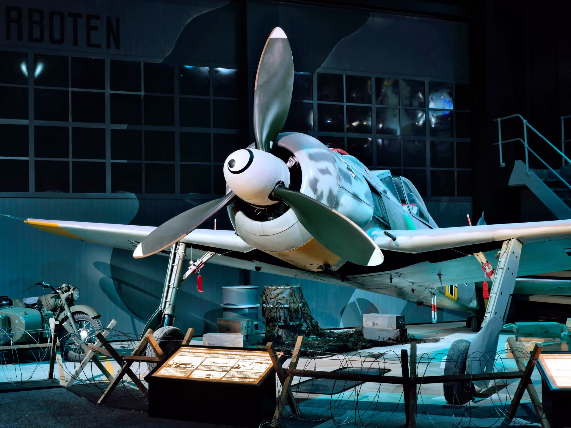 A small aircraft with a shark face paint inside a hangar.