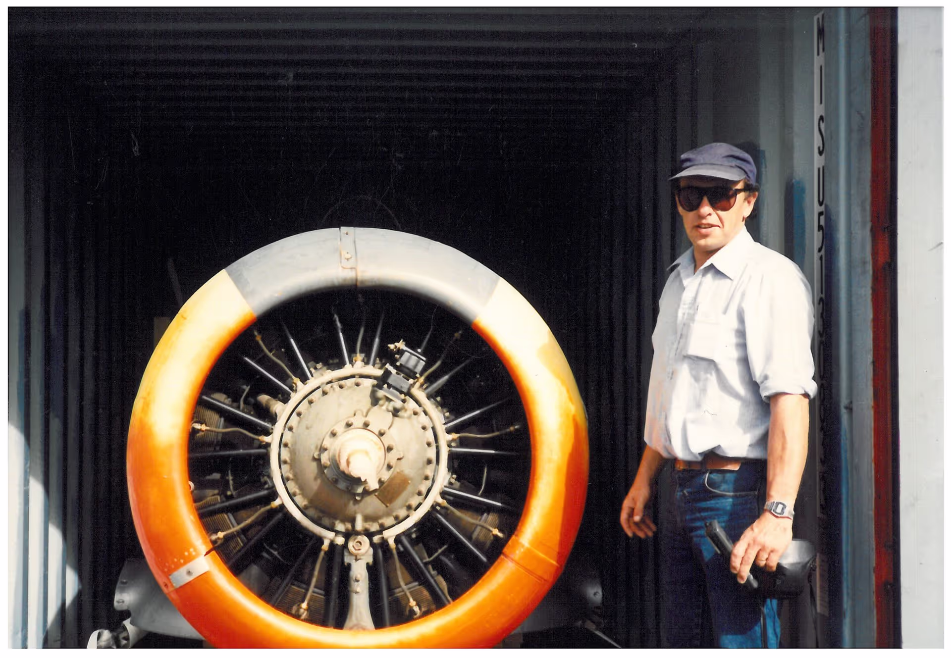 A person standing next to an exposed aircraft engine inside a hangar.